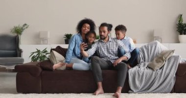 Afrikalı aileler akıllı telefondaki komik uygulamaları kullanarak kanepede dinleniyorlar.