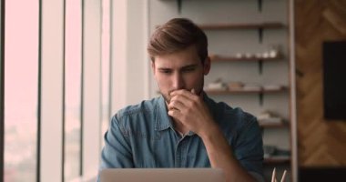 Ciddi ofis müdürü iş yerinde oturup dizüstü bilgisayarla çalışıyor.