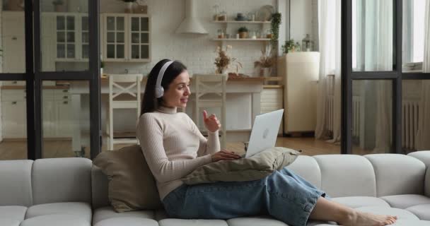 Женщина отдыхает на диване, используя компьютерный разговор с помощью приложения для видеоконференций — стоковое видео