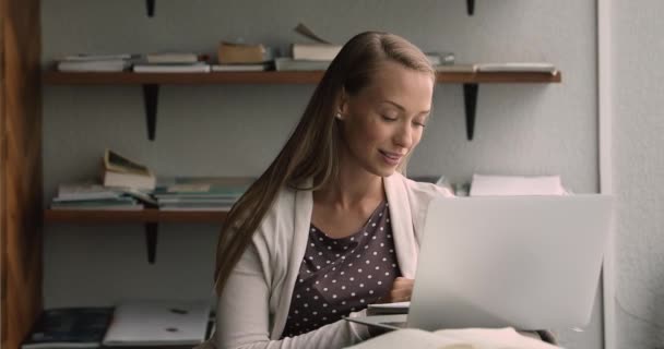 Задумчивая студентка-фрилансер делает заметки о работе с ноутбуком — стоковое видео