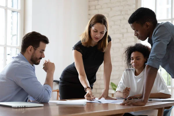 Giovane leader del team femminile che analizza le statistiche con colleghi di razza mista. — Foto Stock