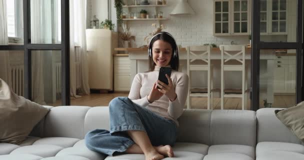 Nő visel vezeték nélküli fejhallgató kommunikál videocall alkalmazás okostelefon — Stock videók