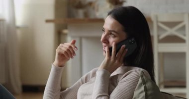 Genç bayan kanepede oturup telefonda keyifli sohbetlerin tadını çıkar.