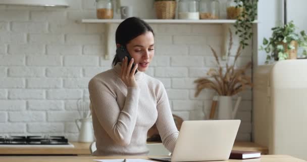 Mujer joven hablando por teléfono pidiendo bienes utilizando el sitio web de comercio electrónico — Vídeos de Stock