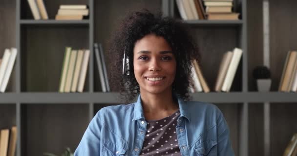 Mulher africana usa fones de ouvido olhando para a câmera conversando via videoconferência — Vídeo de Stock