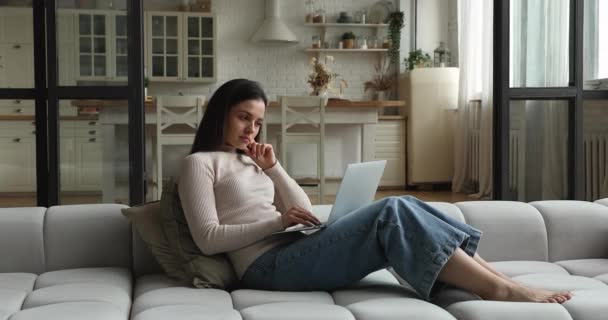 在无线计算机上工作的女性坐在家里的沙发上 — 图库视频影像