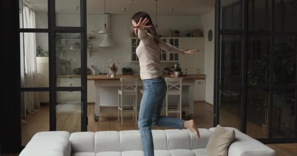 Jeune femme heureuse active insouciante danse sur le canapé à la maison — Video