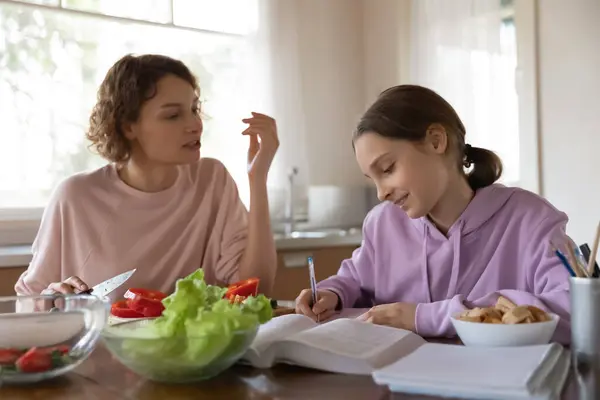 Gelukkig moeder helpen jong tiener dochter met huiswerk. — Stockfoto