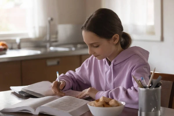 Enfocado adolescente niña estudiando solo en la cocina. —  Fotos de Stock