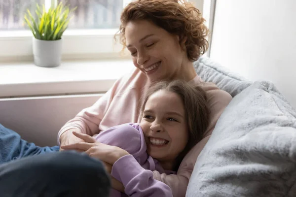 Gelukkig jong moeder kietelen tiener kind dochter. — Stockfoto