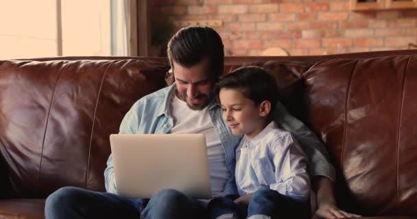 Ο μπαμπάς και ο γιος συζητούν αγορά στο διαδίκτυο χρησιμοποιώντας φορητό υπολογιστή — Αρχείο Βίντεο