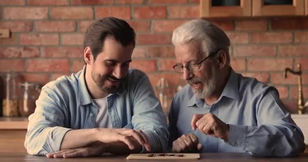 Alegre pai idoso jogar damas com filho adulto em casa — Vídeo de Stock