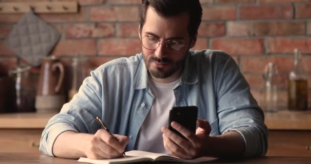 Man schrijft nuttige informatie in persoonlijke organisator genomen van internet — Stockvideo