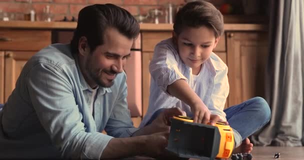 Padre e hijo pequeño reparando camión de juguete juegan juntos en interiores — Vídeo de stock