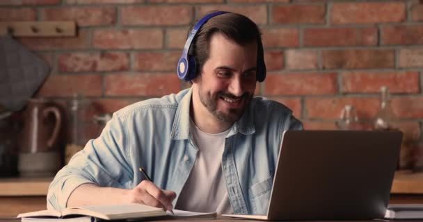 Молодой человек носить наушники слушать аудио курс делает назначение — стоковое видео