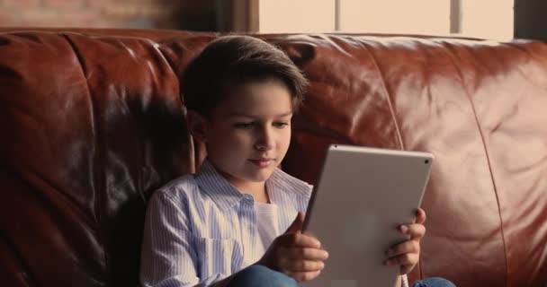 Little boy sit on couch holding tablet play video games — Stock Video