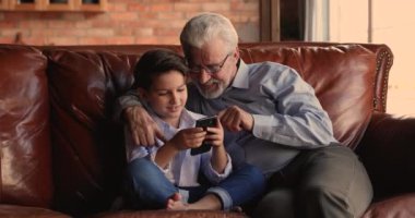 Büyükbaba, küçük torununun cep telefonuyla oyun oynamasını izle.