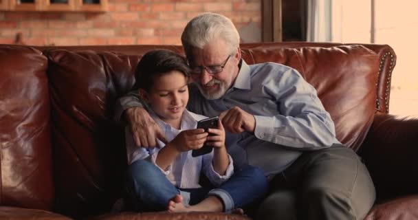 Avô assistir como seu neto jogar videogame no celular — Vídeo de Stock