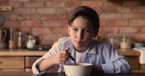 小さな男の子はミルクとおいしいコーンフレークを食べるテーブルに座って — ストック動画