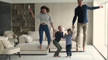 Ebeveynler ve çocuklar el ele tutuşup ağır çekimde zıplıyorlar