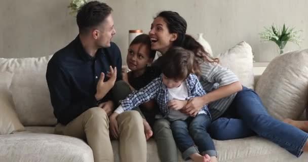 Šťastný pár sedět na pohovce hrát s malými roztomilými dětmi — Stock video