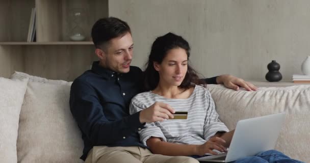 Casal sentar no sofá segurando cartão de crédito compra na internet — Vídeo de Stock