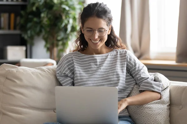 Smiling young woman work online on laptop at home