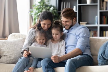 Mutlu ebeveynler ve küçük kızlar dizüstü bilgisayar kullanır.