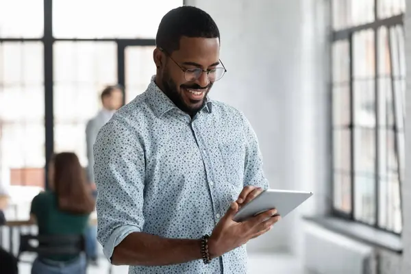 Glad svart manlig anställd läser på digital enhet skärm — Stockfoto