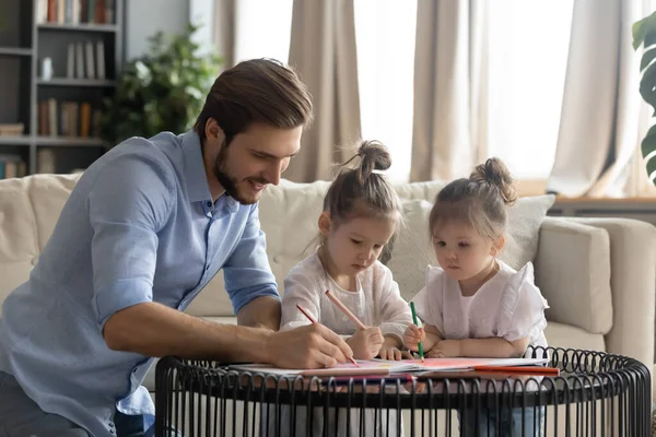 Zorgvuldige vader tekening in album met kleine dochters — Stockfoto