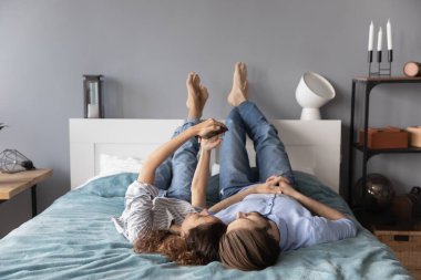 Genç çift yatak odasında birlikte akıllı telefon kullanıyor.