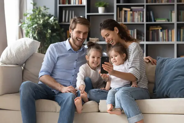 Gelukkig ouders gebruiken mobiele telefoon met twee kleine dochters — Stockfoto