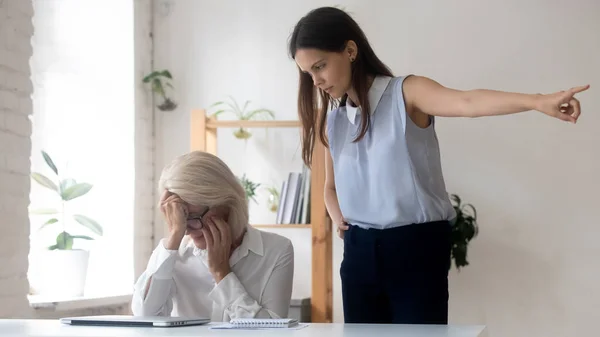 怒っている若いビジネスマン女性が中年女性従業員を解雇 — ストック写真