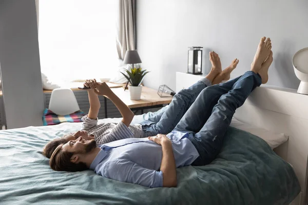 Pasangan bahagia bersantai di kamar tidur menggunakan smartphone — Stok Foto