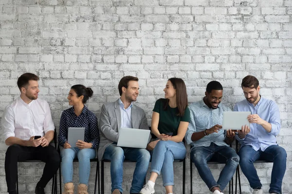 Diverse millennial people with different gadgets talking and laughing — Stock Photo, Image