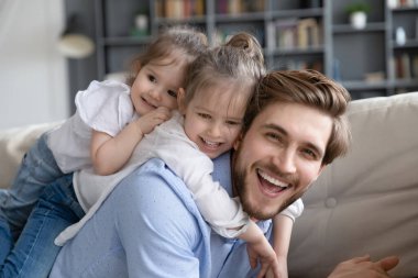Gülümseyen babanın portresi küçük kızlarla oynuyor.