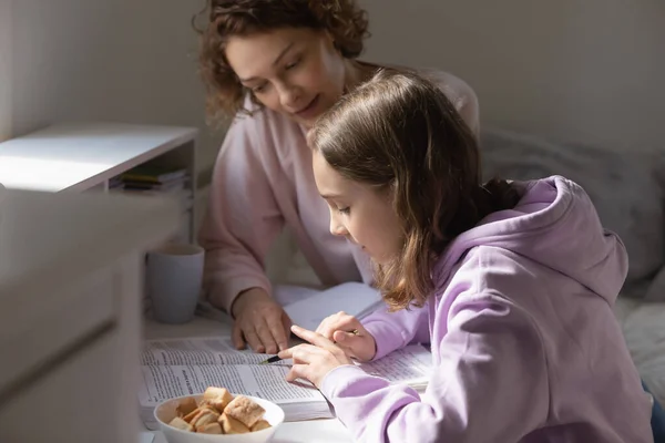 Caring young mother helping teenage kid with homework. — Stock Photo, Image