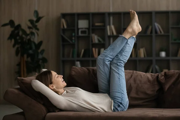 Casual joven hembra relajarse descalzo en sofá levantar las piernas — Foto de Stock