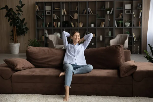 Ruhige junge Frau sitzt in entspannter Haltung auf bequemem Sofa — Stockfoto