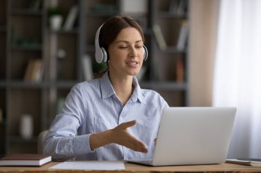 Kablosuz kulaklıklı genç bayan bilgisayar ekranından konuşuyor.