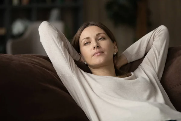 Tranquil teenage female lie on couch with hands behind head — Stock Photo, Image