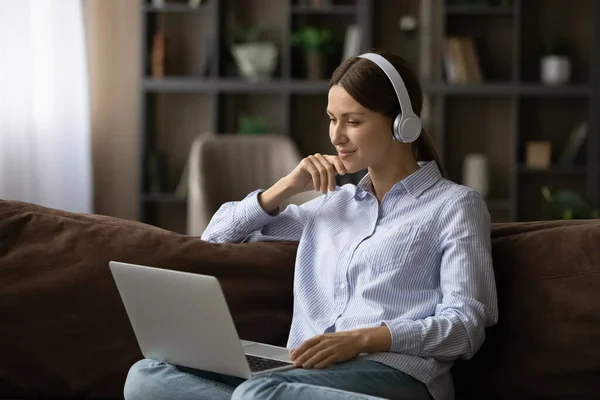 Sorrindo adolescente fêmea em fones de ouvido desfrutar de filme online no laptop — Fotografia de Stock