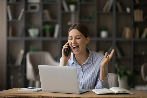 Excited young lady chat by phone at workplace discuss achievement — Stock Photo, Image