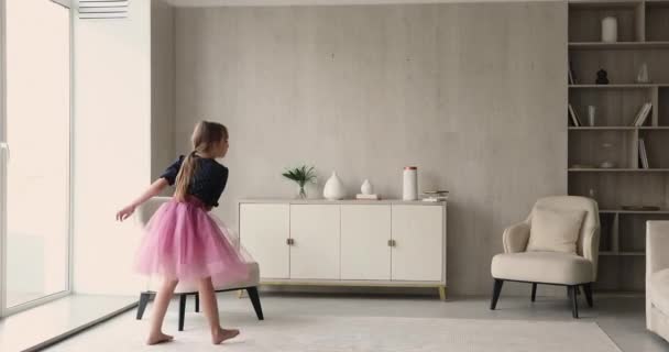 Kleines Mädchen trägt rosa flauschigen Rock tanzen im Wohnzimmer — Stockvideo