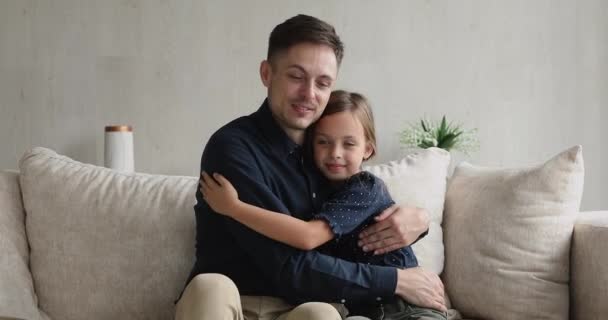 Liefhebbende vader en kleine dochter knuffelen zittend op bank — Stockvideo