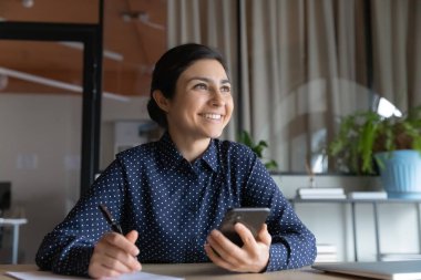 Mutlu Hintli kadın akıllı telefonla çalışıyor, planlar yapıyor.