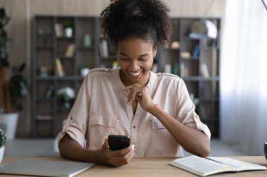 Gülümseyen Afrikalı Amerikalı iş kadını akıllı telefon uygulaması kullanıyor..