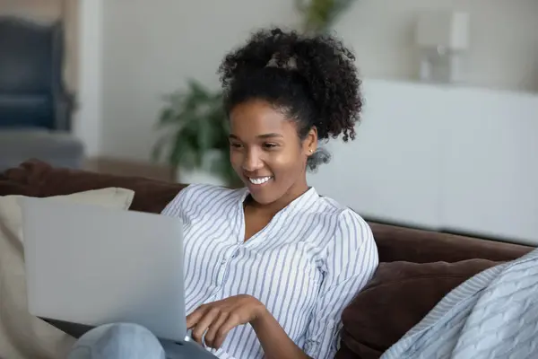 Lächelnde afrikanische Millennial-Frau nutzt Computer zu Hause. — Stockfoto