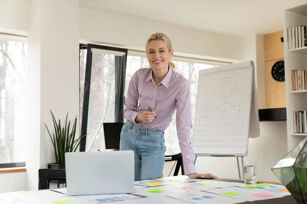 Porträt einer selbstbewussten erfolgreichen Geschäftsfrau, die im Amt am Tisch steht — Stockfoto