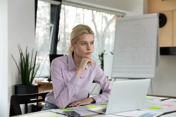 Femme d'affaires réfléchie assis à la table avec ordinateur portable, la stratégie de réflexion — Photo